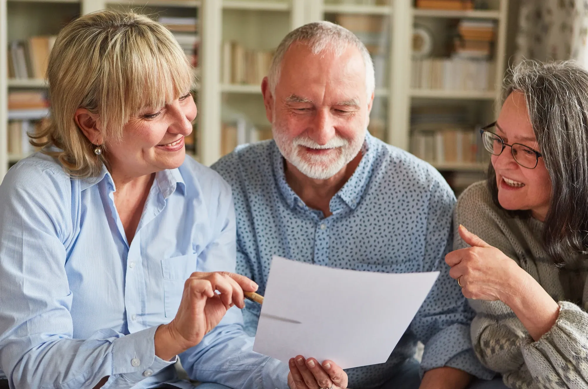 Three older adults reviewing a document together at home