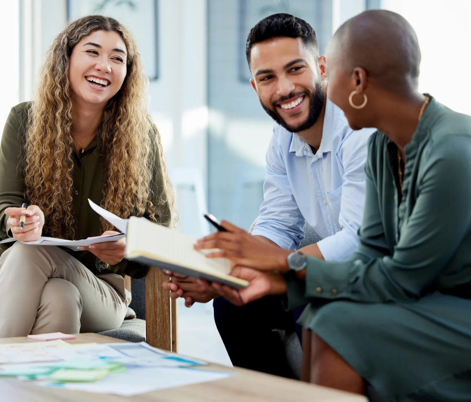 Three coworkers smiling during a benefits planning conversation